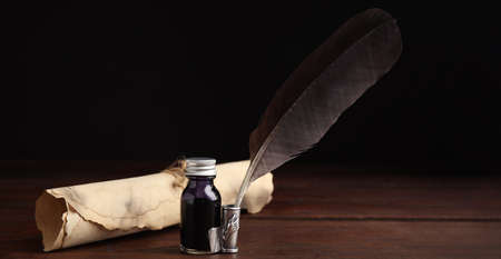 Quill, bottle of ink and parchment scroll on wooden table. banner designの写真素材