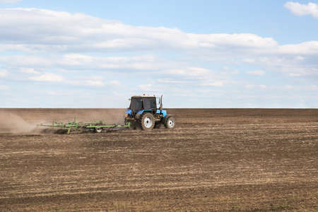 Tractor with planter cultivating field on sunny day. agricultural industry