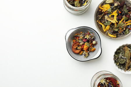 Different dry herbs and tea on white background, flat lay. Space for text