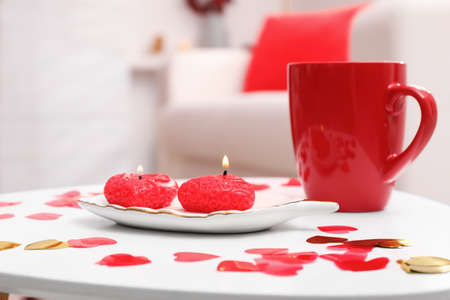 Red cup, candles and heart shaped confetti on white table indoors. Valentine's Day celebrationの写真素材