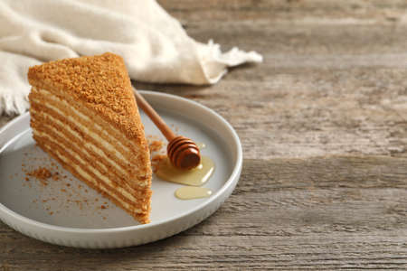 Slice of delicious layered honey cake served on wooden table. Space for textの写真素材