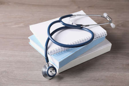Student textbooks and stethoscope on wooden table. medical education