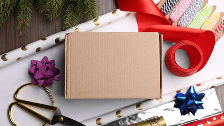 Box, wrapping paper and scissors on wooden table, flat lay