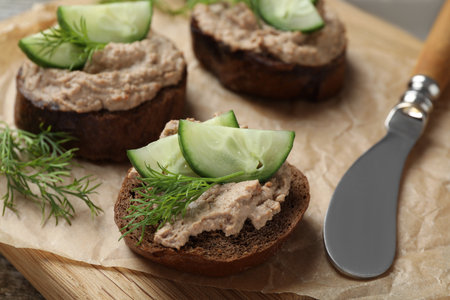 Slices of bread with delicious pate, cucumber and dill on wooden board, closeupの写真素材