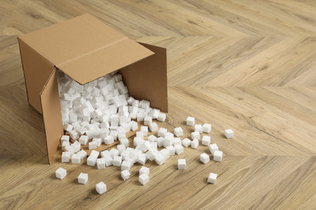 Overturned cardboard box with cubes on wooden floor. Space for text