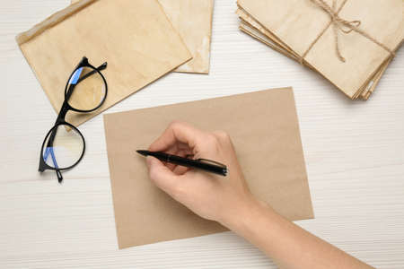 Woman writing letter on white wooden table, top viewの写真素材