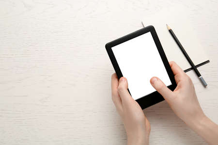 Woman using e-book reader on white wooden table, top view. Space for textの写真素材