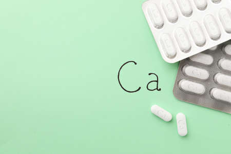 Blister packs with calcium supplement pills on light green background, flat lay. Space for textの写真素材