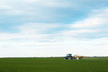 Tractor spraying pesticide in the field on spring day. agricultural industry