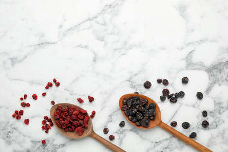 Dried red and black currant berries on white marble table, flat lay. Space for text