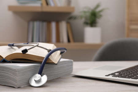 Book, stethoscope, laptop and stack of documents on table indoors, space for text. medical educationの写真素材