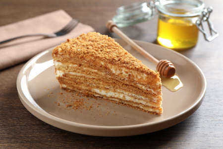 Slice of delicious layered honey cake served on wooden tableの写真素材