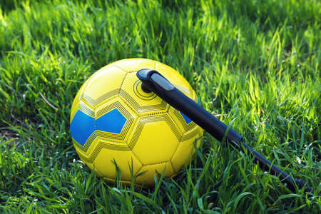 Soccer ball with manual pump inflator on green grassの写真素材