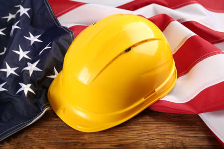 Yellow protective hard hat and American flag on wooden tableの写真素材