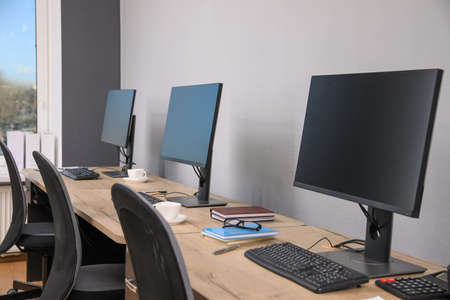 open office interior. Modern workplaces with computers near light gray wall