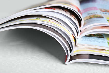 Many open magazines on white wooden table, closeupの写真素材