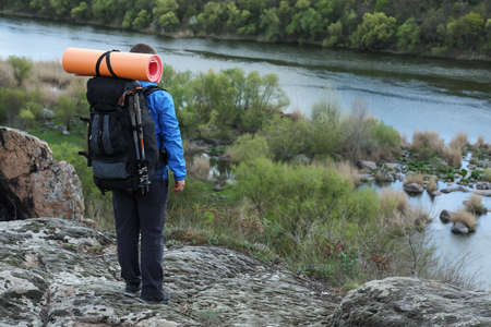 Hiker with backpack ready for journey on rocky hill, back viewの写真素材