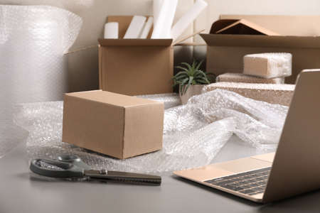 Table with laptop, boxes and   wrap in warehouseの写真素材