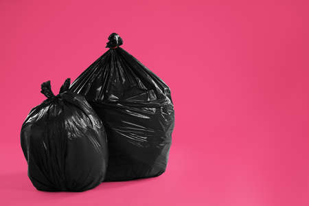 Trash bags full of garbage on pink background. Space for textの写真素材