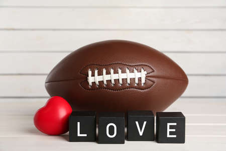 American football ball, heart and cubes with word Love on white wooden tableの写真素材