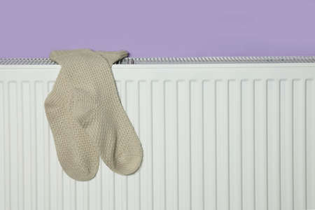 Beige socks on heating radiator near violet wallの写真素材