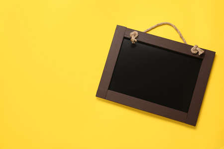 Clean small black chalkboard on yellow background, top view. Space for textの写真素材
