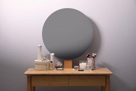 Stylish dressing table with cosmetics, mirror and accessories near white wall