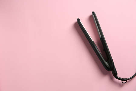 Modern flat hair iron on pink background, top view. Space for textの写真素材