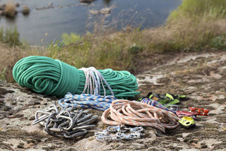 Different ropes and other climbing equipment on rock near riverの写真素材
