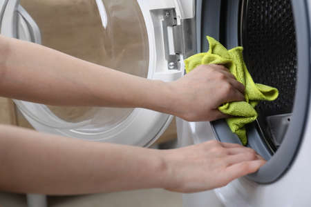 Woman cleaning washing machine with rag indoors, closeupの写真素材