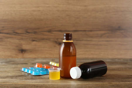 Cough syrup and lozenges on wooden table