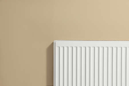 Modern radiator on beige wall, space for text. central heating system