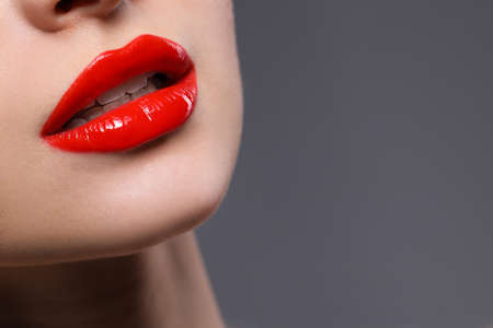 Young woman with beautiful red lips on gray background, closeup. Space for textの写真素材