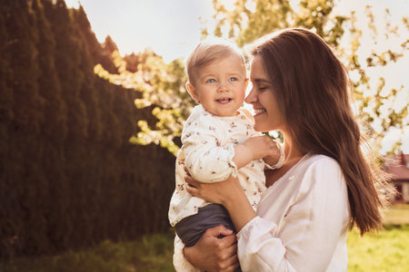 Happy mother with her cute baby in park on sunny day