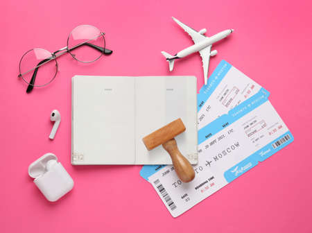Flat lay composition with passport, stamp and flight tickets on pink background