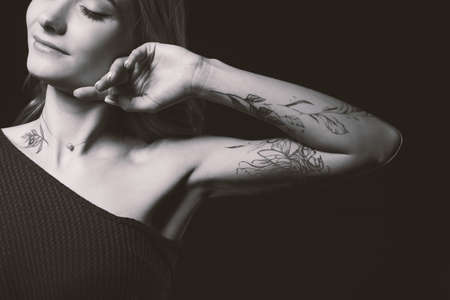 Young woman tattoo on dark background. black and white photography