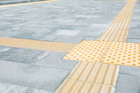 Gray pavement with tactile tiles outdoors. Public environment accessible for visually impaired