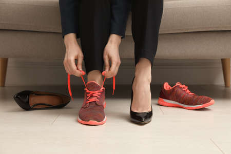 Woman changing shoes on sofa in office, closeupの写真素材