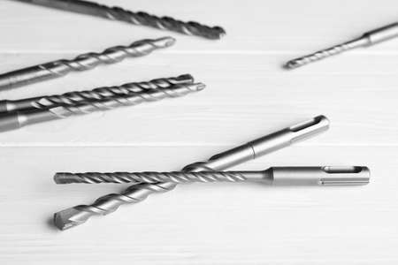 Different drill bits on white wooden table