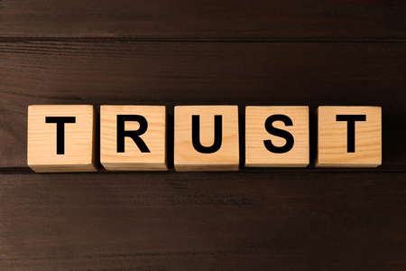 Cubes with word TRUST on wooden table, flat layの写真素材