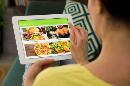 Woman using tablet for ordering food online at home, closeup. Concept of delivery serviceの写真素材