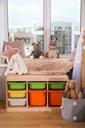 Stylish child room with storage for toys near windowの写真素材