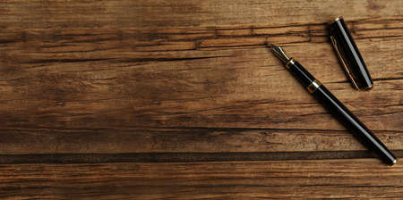 Beautiful fountain pen on wooden table, top view with space for text. banner designの写真素材