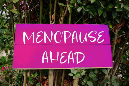 Concept of impending climacteric. Green bush with sign MENOPAUSE AHEAD outdoorsの写真素材