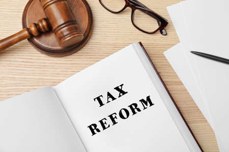 Book with text TAX REFORM, gavel and glasses on wooden background, flat layの写真素材