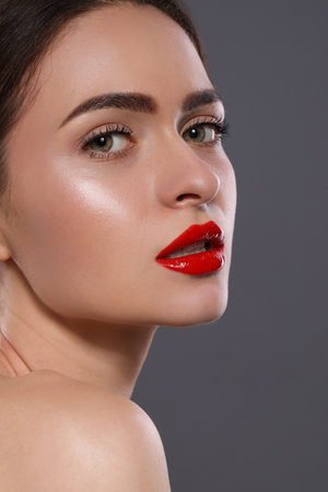 Young woman with red lips makeup on gray backgroundの写真素材