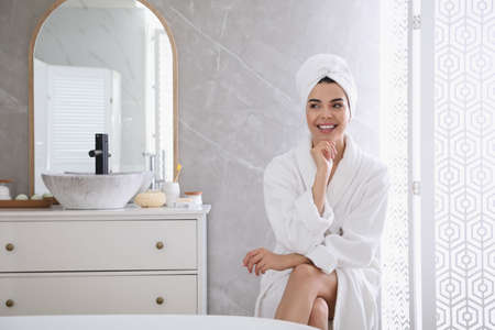 Beautiful young woman wearing soft white robe in bathroom
