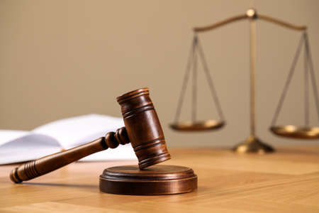 Wooden gavel, open book and scales of justice on table. Space for text