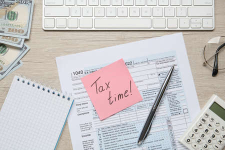 Reminder note with words Tax Time, documents, computer keyboard, money and calculator on white...