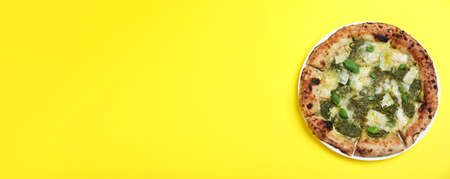 Delicious pizza with pesto, cheese and basil on yellow background, top view with space for text. banner designの写真素材